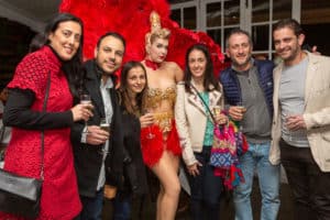 Group of guests posing with a glamorous burlesque performer at a themed event in Sydney